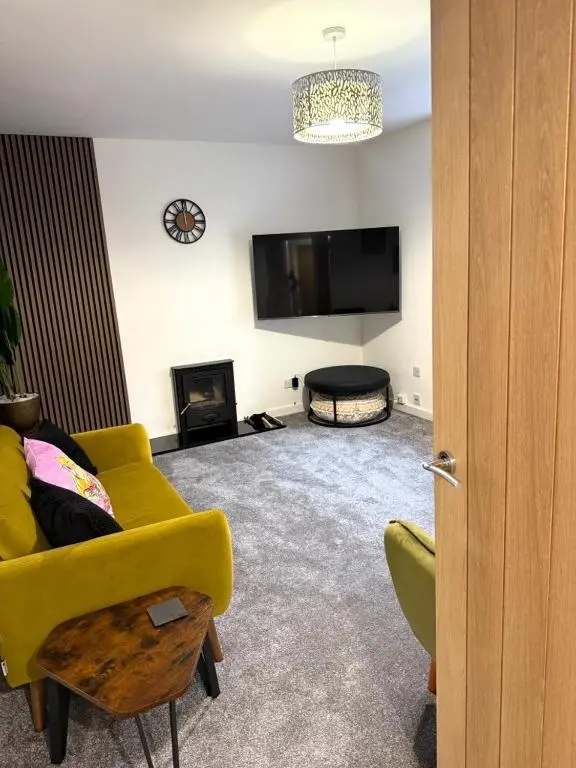 a living room with a yellow couch and a tv at Meadowside-Stylish Newly Renovated 2 bed property in Insch