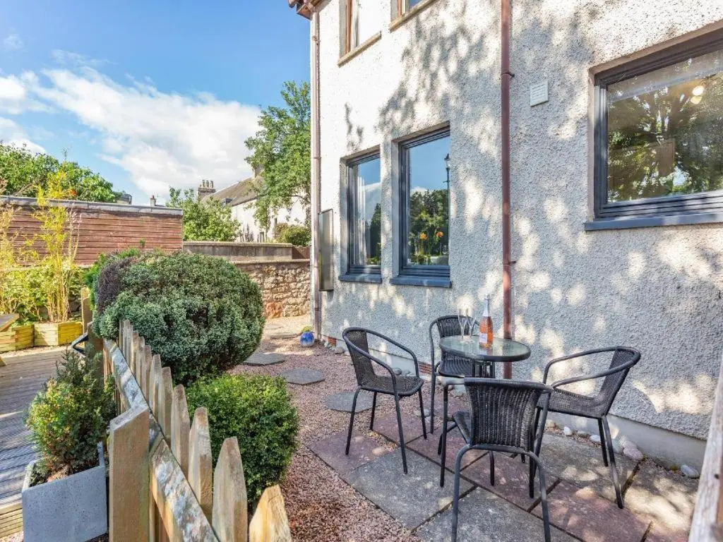 a patio with chairs and a table in front of a building at River views 5 mins from beach in Nairn