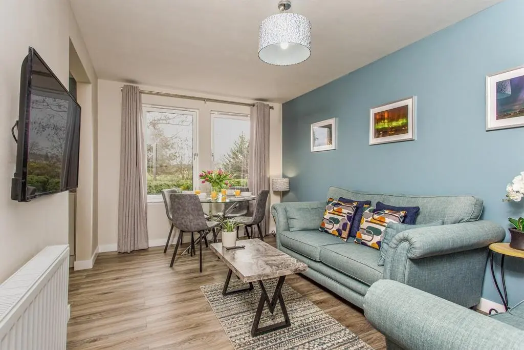 a living room with a couch and a table at River views 5 mins from beach in Nairn