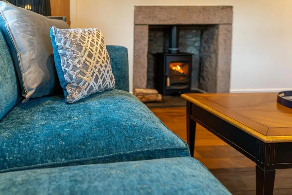 a blue couch in a living room with a fireplace at Old Coach House in Braemar
