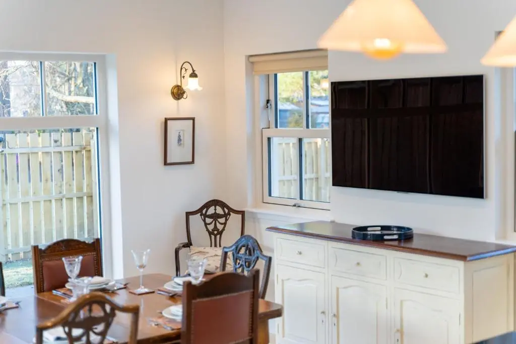 a dining room with a table and a flat screen tv at Old Coach House in Braemar