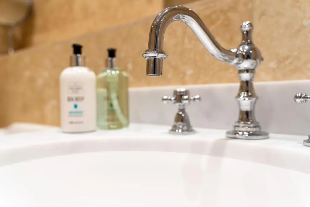 a bathroom sink with two bottles of soap on it at The Old Coach House & The Hayloft in Braemar