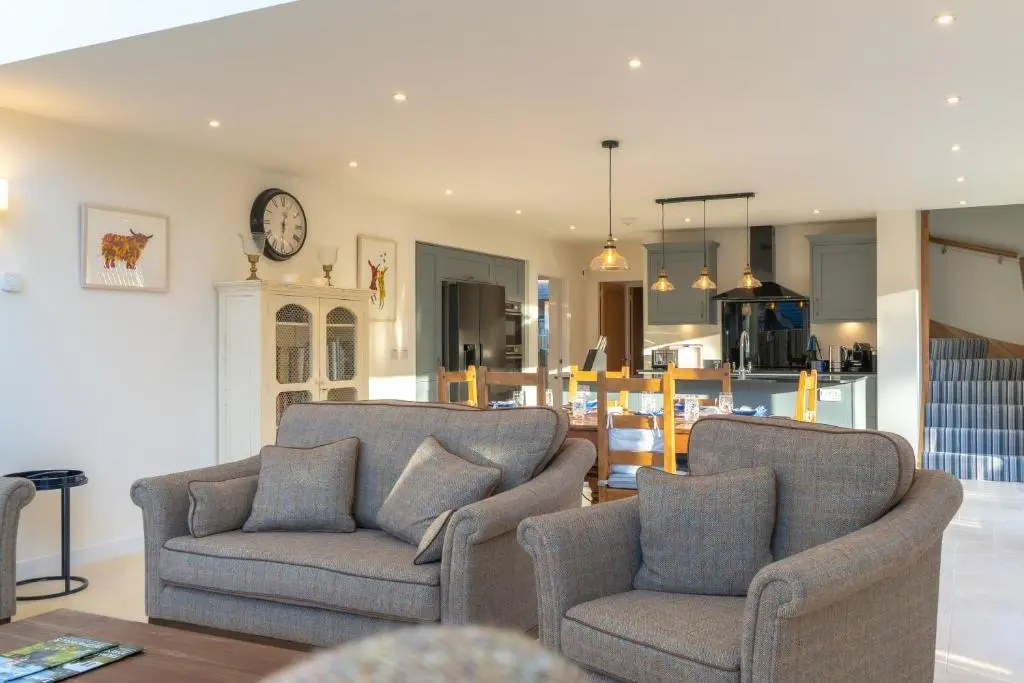 a living room with two chairs and a clock on the wall at The Chalet in Braemar