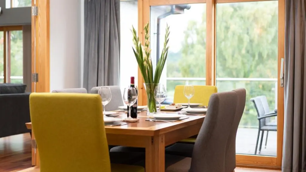 a dining room with a table with yellow chairs at Coorie Lodge in Aviemore