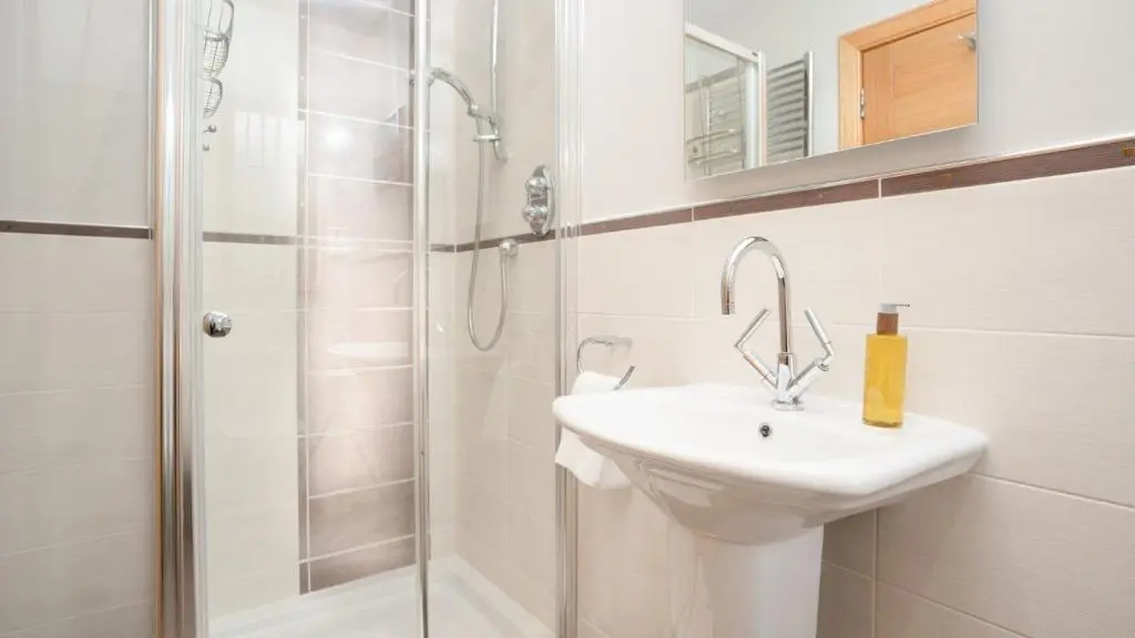 a white bathroom with a sink and a shower at Coorie Lodge in Aviemore