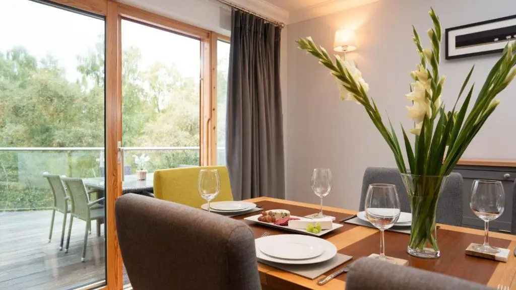 a dining room with a table and chairs and a large window at Coorie Lodge in Aviemore