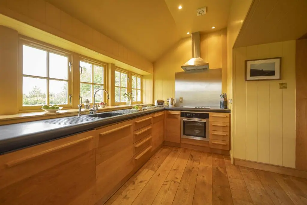 a large kitchen with wooden cabinets and a sink at Drum Cottage in Nethy Bridge