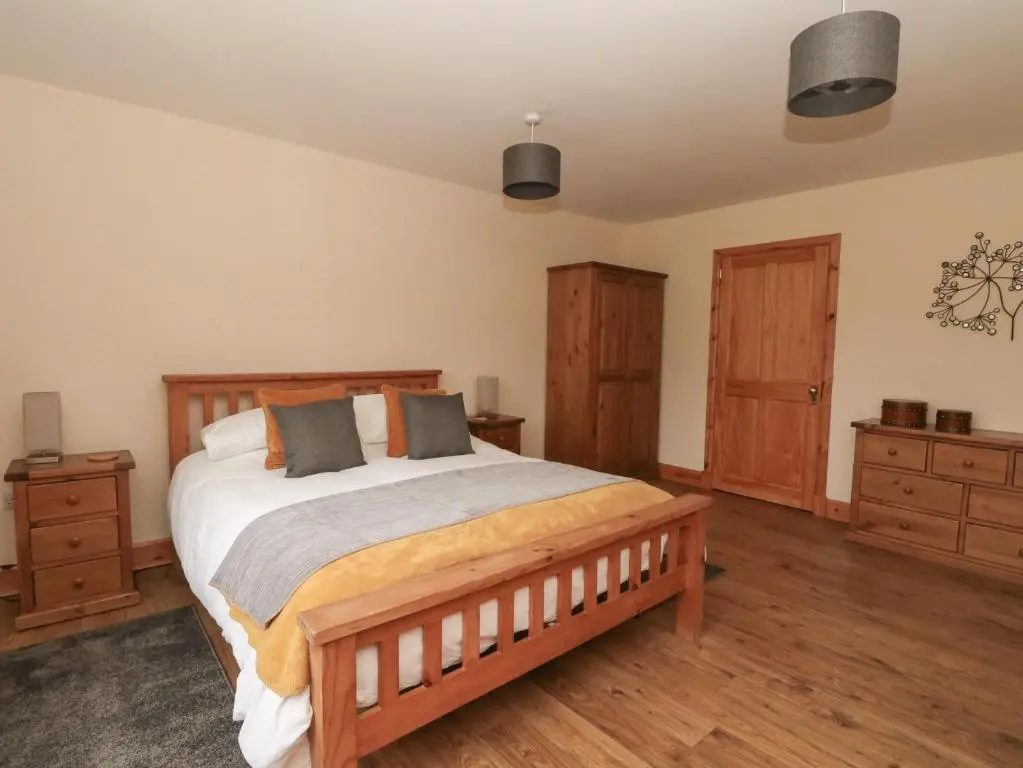 a bedroom with a large bed and wooden furniture at Taffs Barn in Fortrose