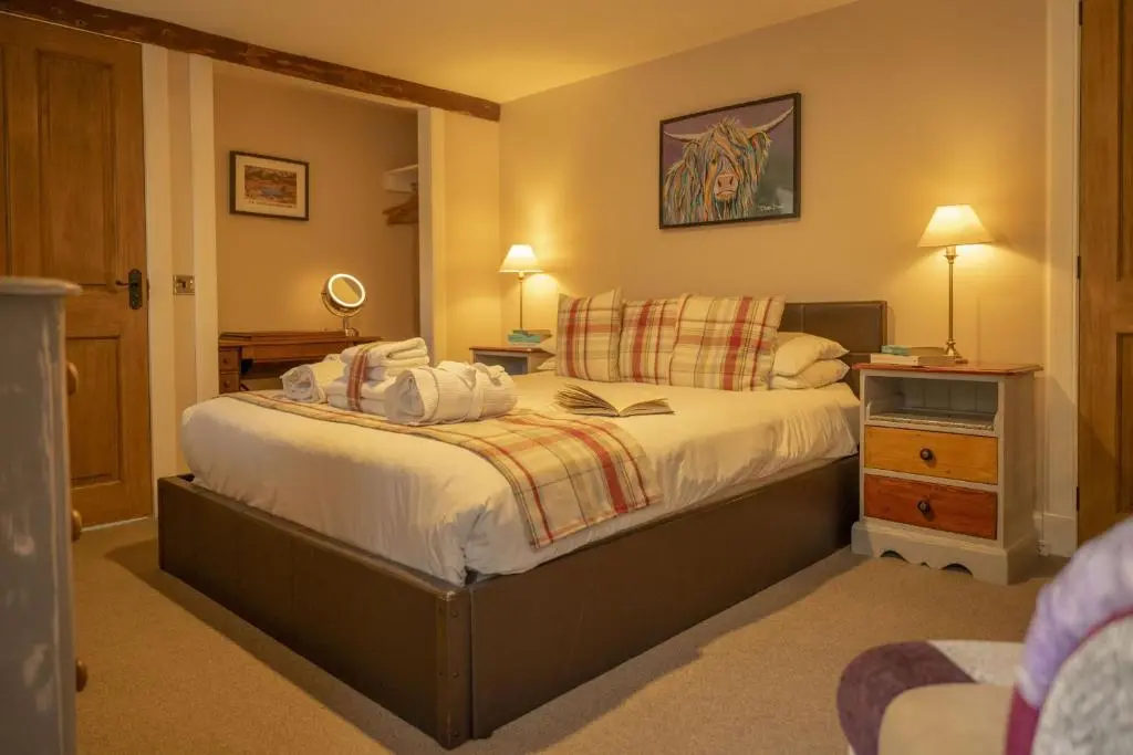 a bedroom with a large bed with white sheets at Craggan Mill in Grantown on Spey
