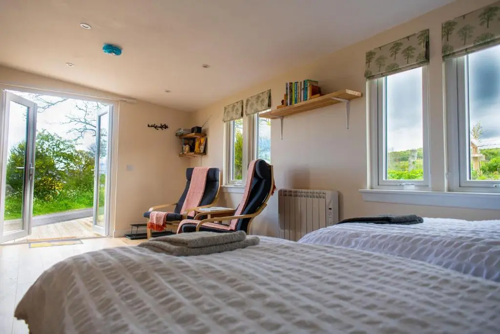 a bedroom with two beds and two chairs and windows at The Drey Inchberry