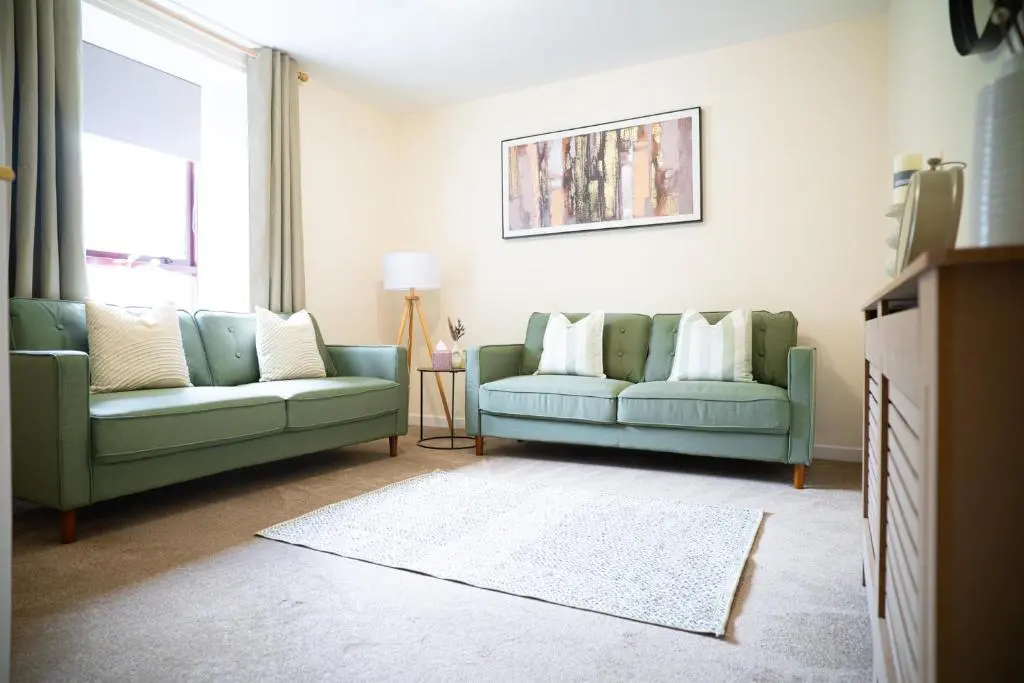 a living room with two green couches and a window at Innes Street Apartment in Inverness
