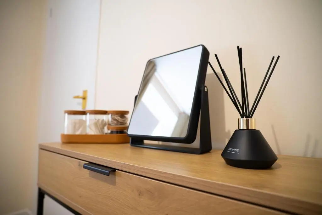 a computer monitor and a vase with sticks on a dresser at Innes Street Apartment in Inverness