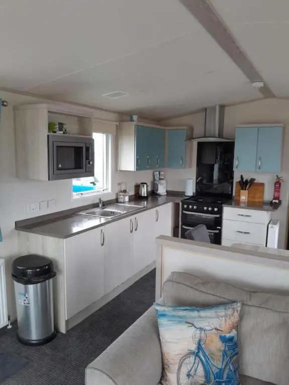 a kitchen with white cabinets and a couch in it at H26atsilversands in Lossiemouth