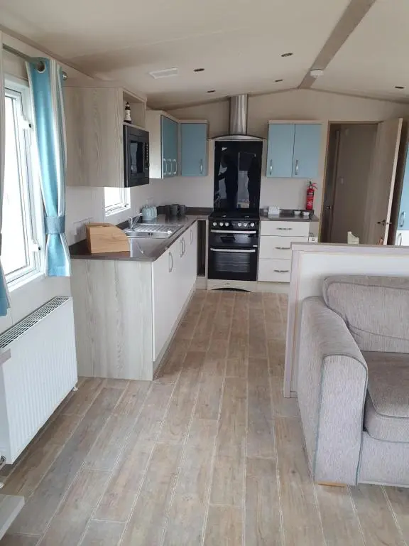 a kitchen with blue cabinets and a couch in it at H26atsilversands in Lossiemouth