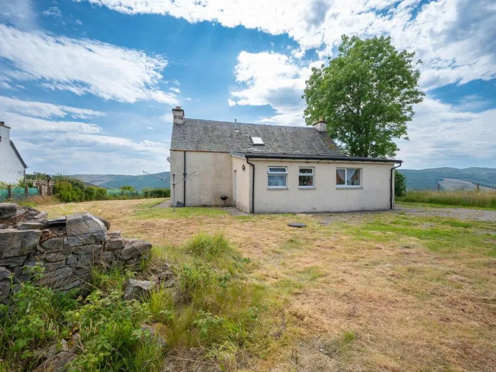 an old white house in a field with a tree at Holiday Home The Manor House by Interhome in Balnain