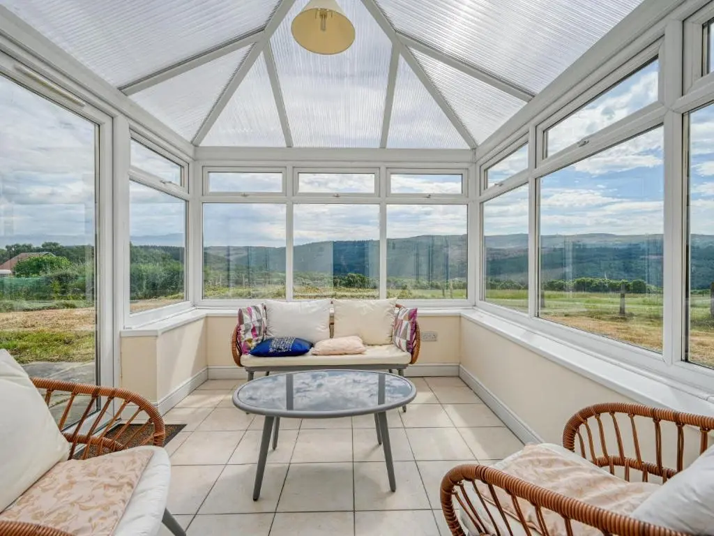 a conservatory with a table and chairs and windows at Holiday Home The Manor House by Interhome in Balnain