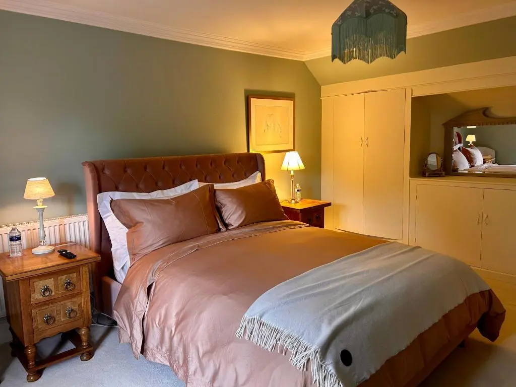 a bedroom with a large bed and a table with lamps at Clashmore House in Dornoch
