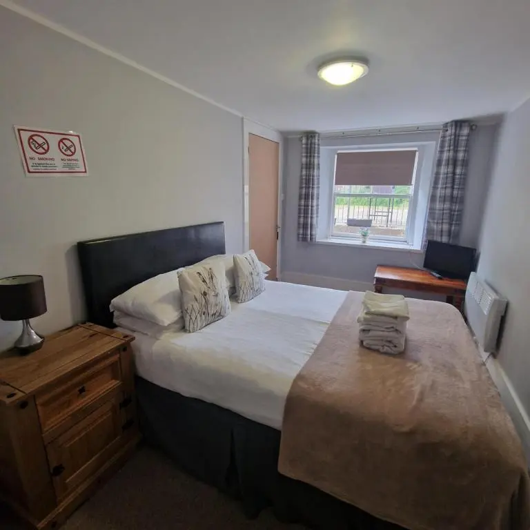 a bedroom with a large bed and a window at Black Isle Holiday Apartments Avoch in Avoch