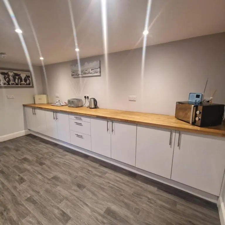 a kitchen with white cabinets and a wooden counter top at Black Isle Holiday Apartments Avoch in Avoch