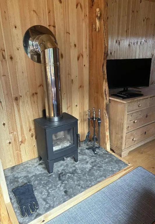 a wood burning stove in a room with a television at Shepherd's Bothy, Bothan a Bhuachaille, Black Isle in Munlochy