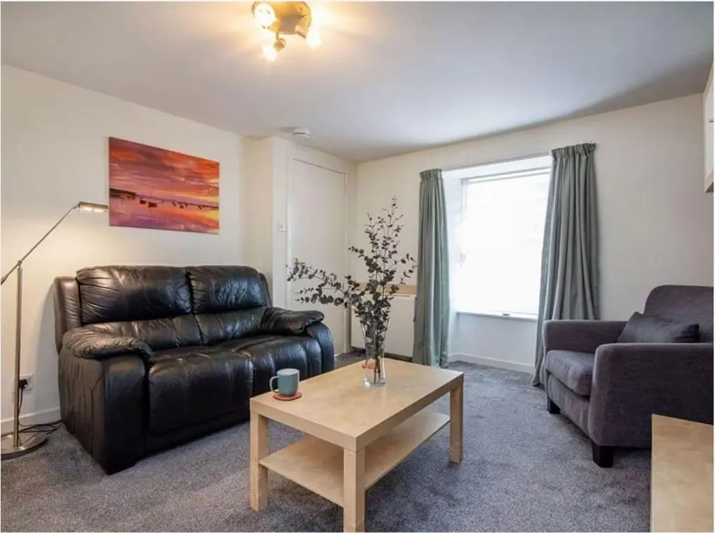 a living room with a leather couch and a coffee table at 1 Bedroom Alexander Cottage-Free Parking in Inverness