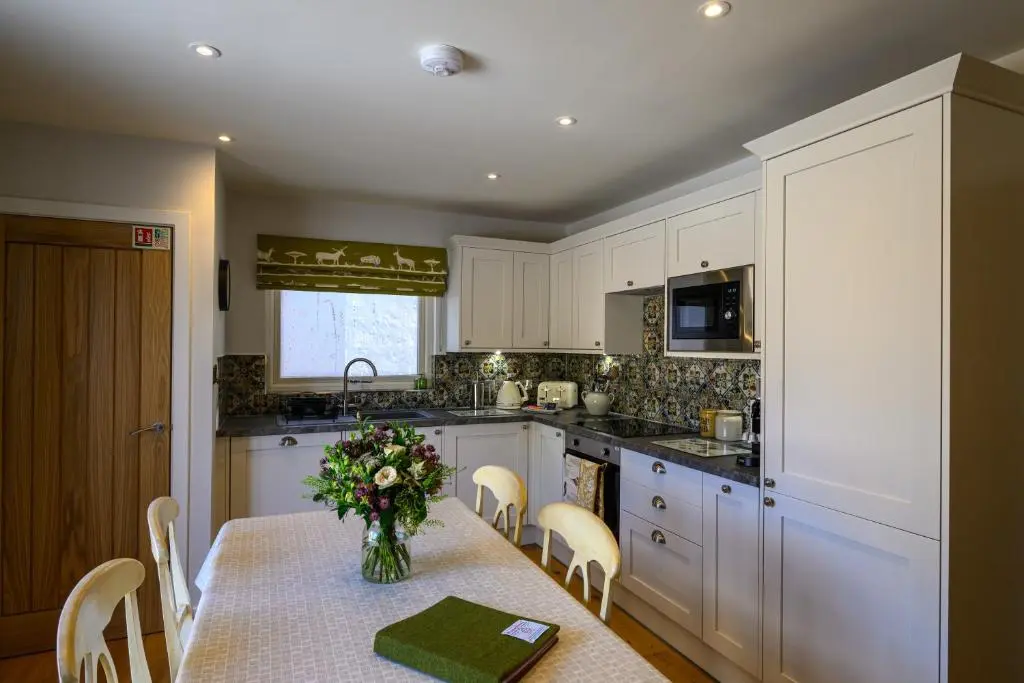 a kitchen with a table with a vase of flowers on it at Harris House in Inverness