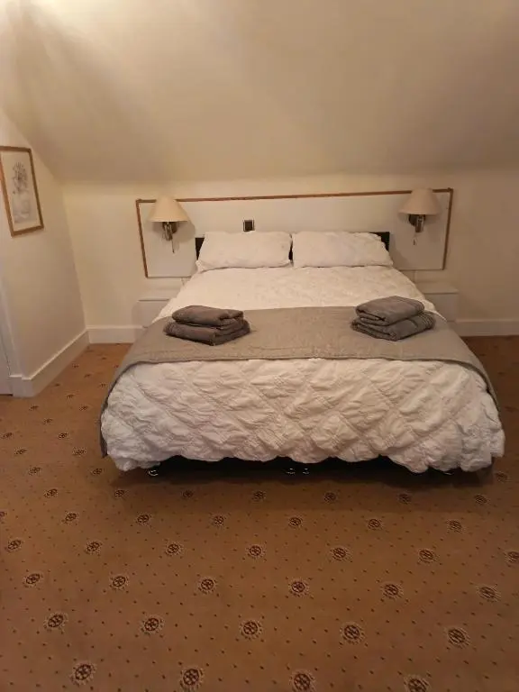 a bedroom with a large bed with two towels on it at River Black Water inn in Garve