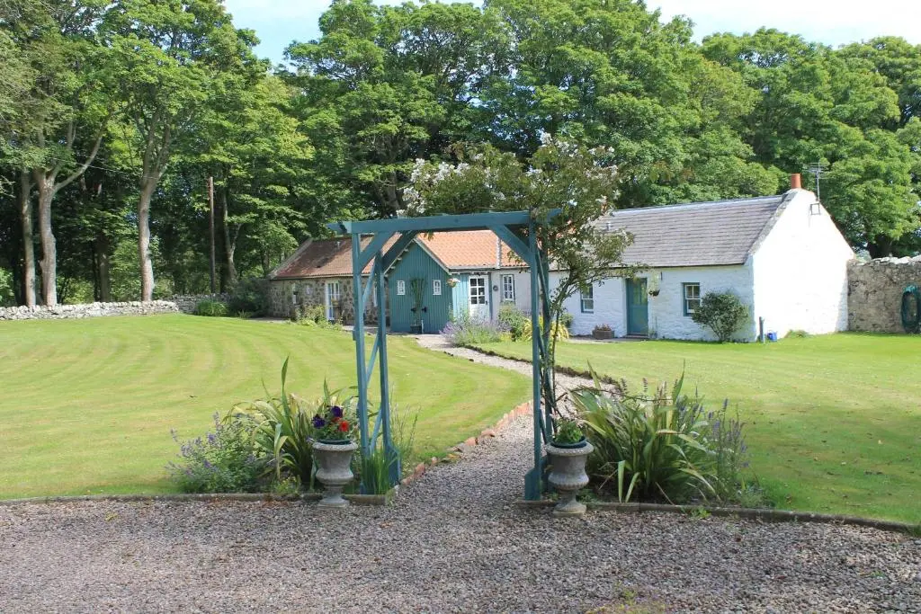 a garden with a blue structure in front of a house at St Brandon House Country Cottages in Boyndie