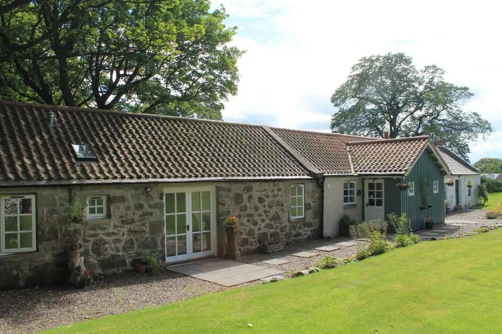 an old stone house with a garden in front of it at St Brandon House Country Cottages in Boyndie
