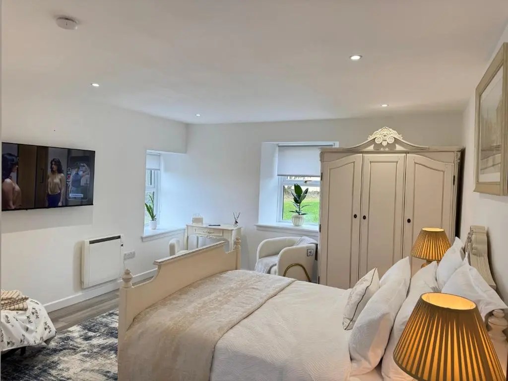 a white bedroom with a large bed with two lamps at Altons Bothy Guest House