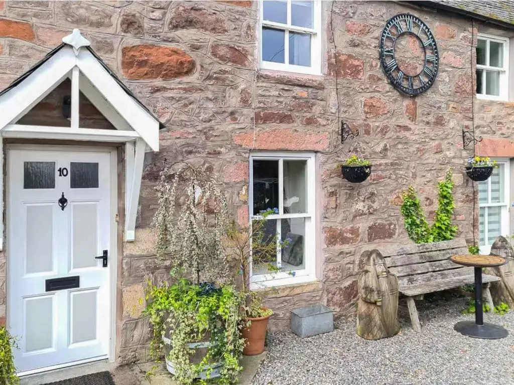 a stone building with a white door and a bench at 1 Bedroom Alexander Courtyard-Free Parking in Inverness