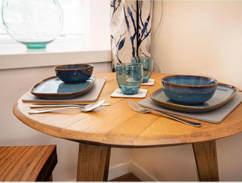 a wooden table with two bowls and glasses on it at 1 Bedroom Alexander Courtyard-Free Parking in Inverness