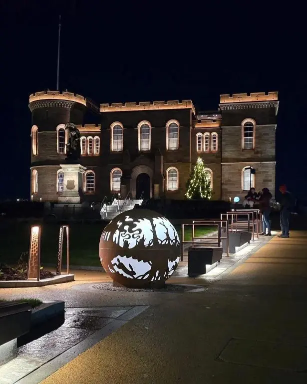 a sculpture in front of a building at night at V\u016b by the Bridge, Inverness City Centre in Inverness
