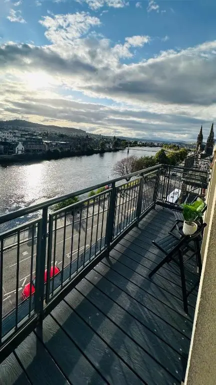 a wooden deck with a view of a river at V\u016b by the Bridge, Inverness City Centre in Inverness