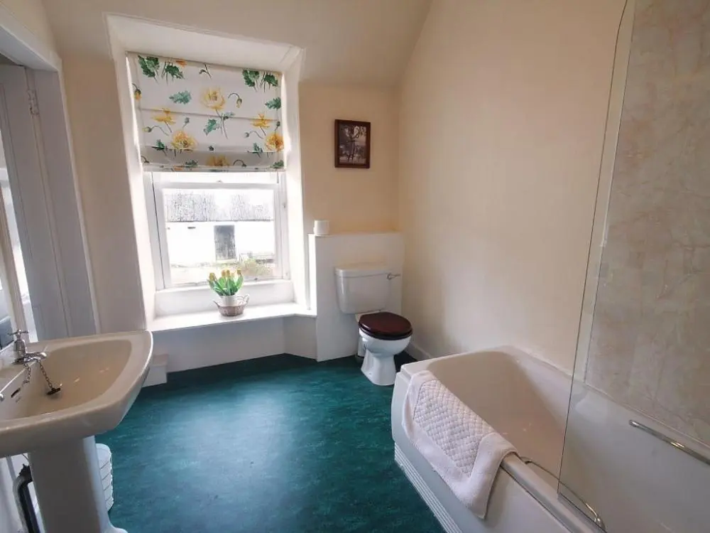 a bathroom with a tub and a toilet and a window at Biallid House in Newtonmore