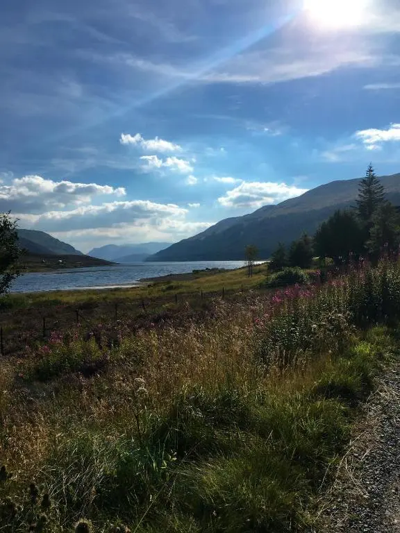 a field of grass next to a body of water at Biallid House in Newtonmore