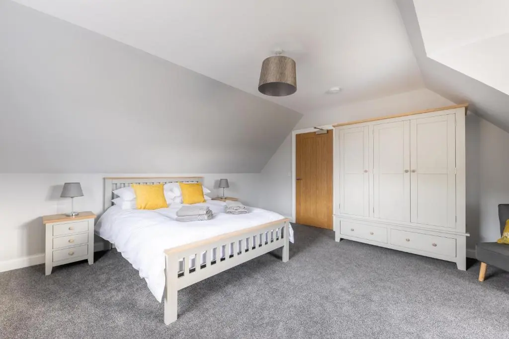 a bedroom with a white bed and a wooden cabinet at Glenview in Tomatin