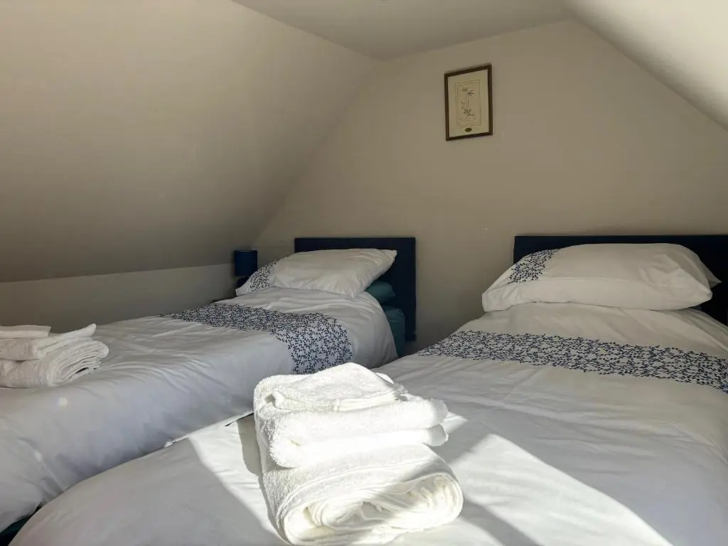 a attic room with two beds with white sheets at Mary Cottage in Garmouth