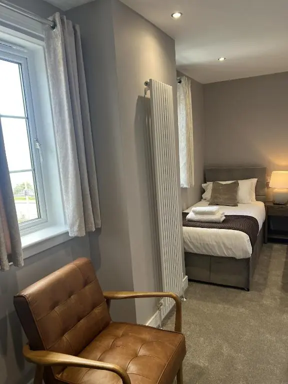a bedroom with a bed and a chair and a window at Tuckers Inn in Invergordon