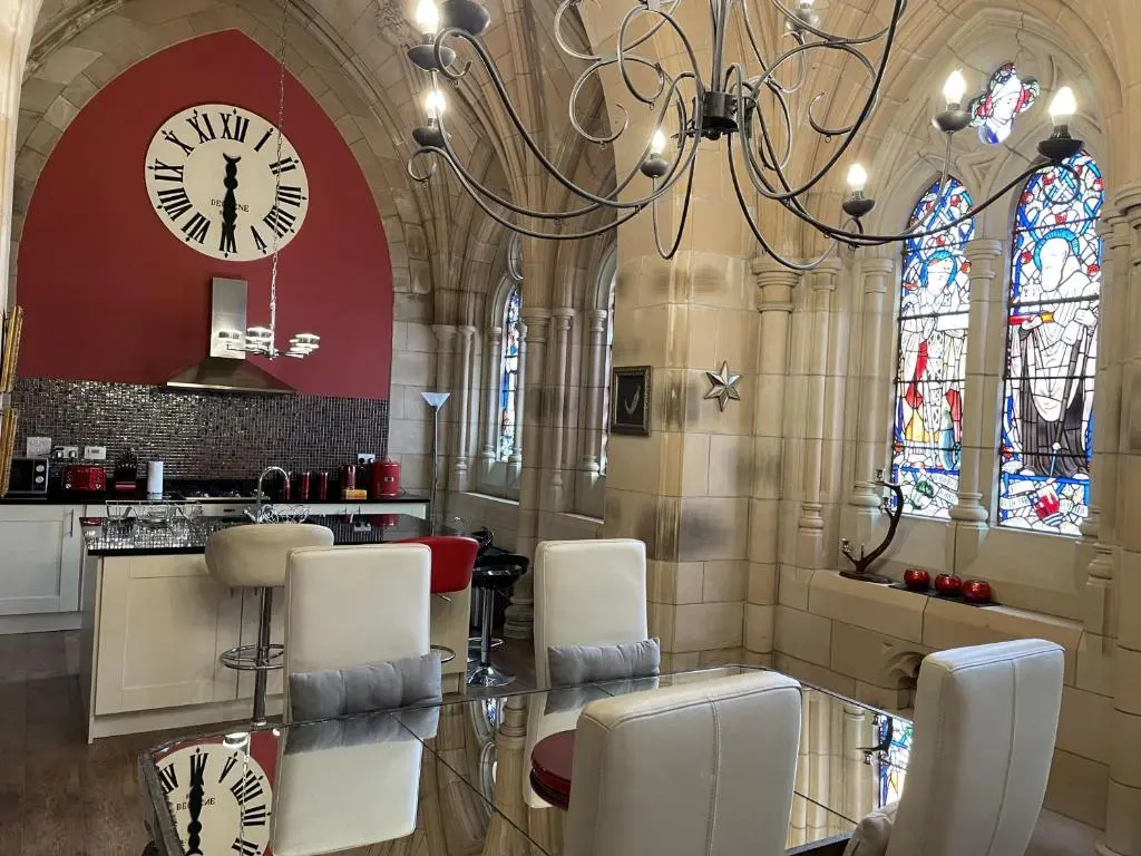 a kitchen with a clock and a table and chairs at Romantic getaway at St Andrew's Chapel in Fort Augustus