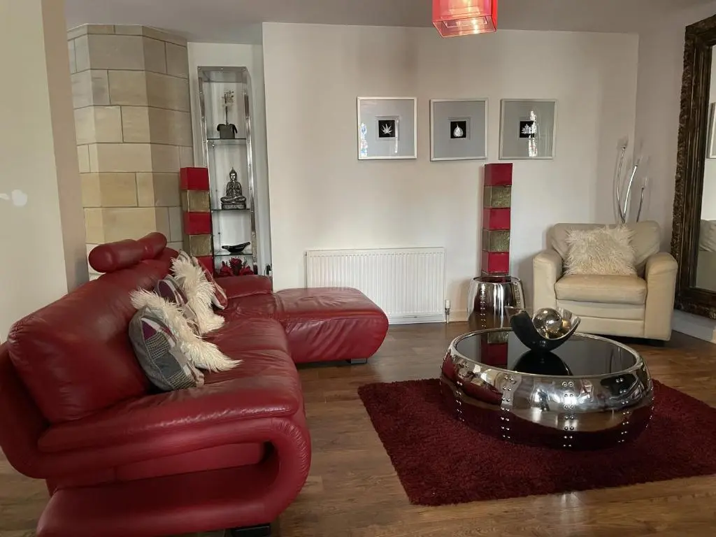 a living room with a red leather couch and a coffee table at Romantic getaway at St Andrew's Chapel in Fort Augustus
