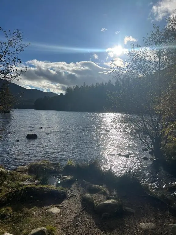 a lake with the sun shining on the water at 6 Carn Dearg House in Aviemore
