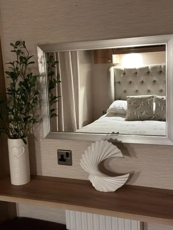 a mirror on a wall with a bed in a bedroom at Jen's Retreat in Lossiemouth