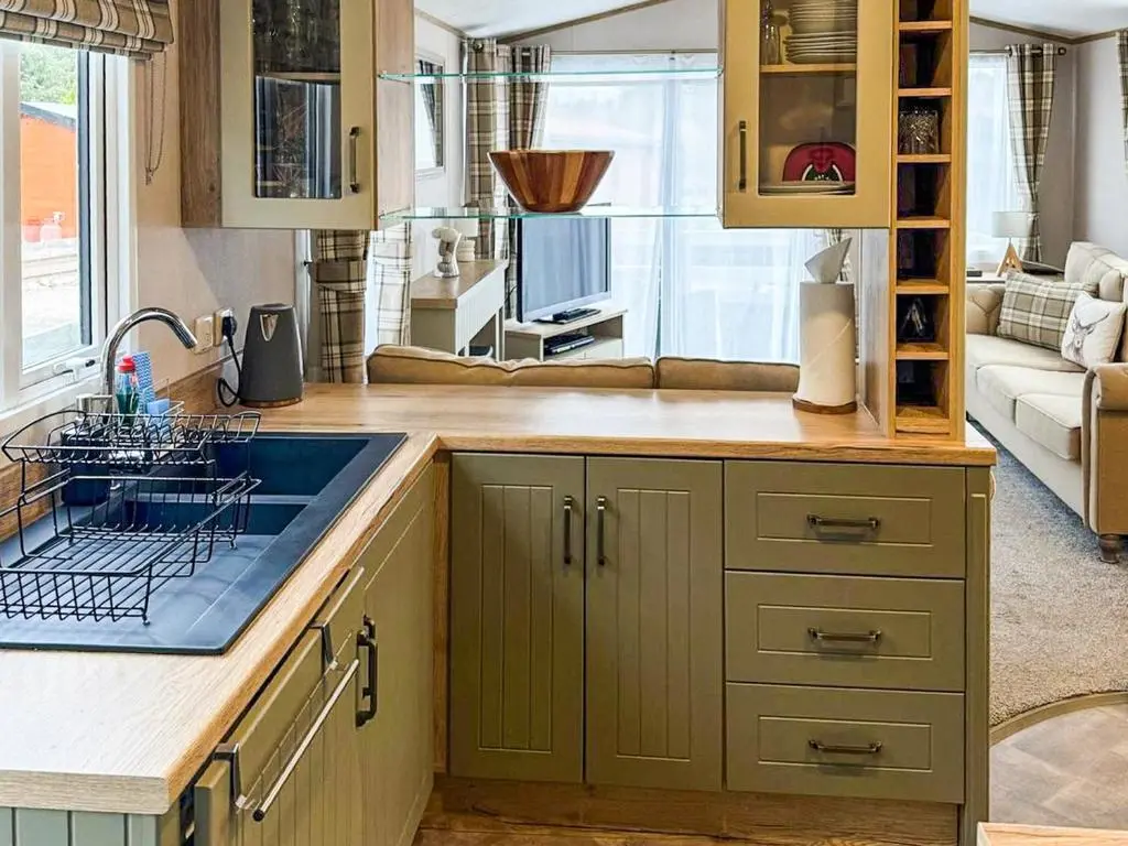a kitchen with green cabinets and a sink at Lodge 58 in Aviemore