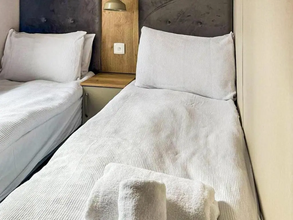 two beds in a small room with white sheets at Lodge 58 in Aviemore