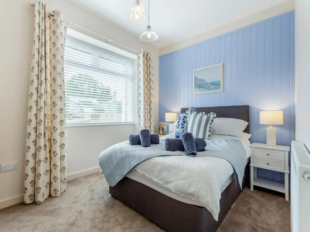 a bedroom with a bed with blue walls and a window at Sea Breezes in Balintore
