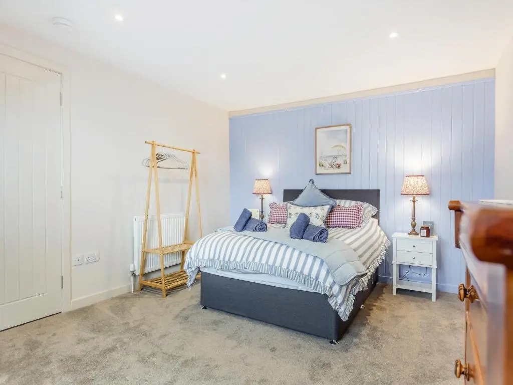 a bedroom with a bed with a blue wall at Sea Breezes in Balintore