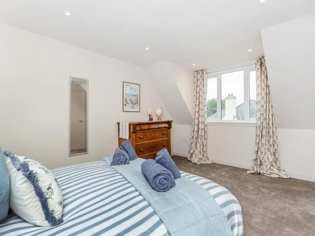 a bedroom with a bed with blue pillows and a window at Sea Breezes in Balintore