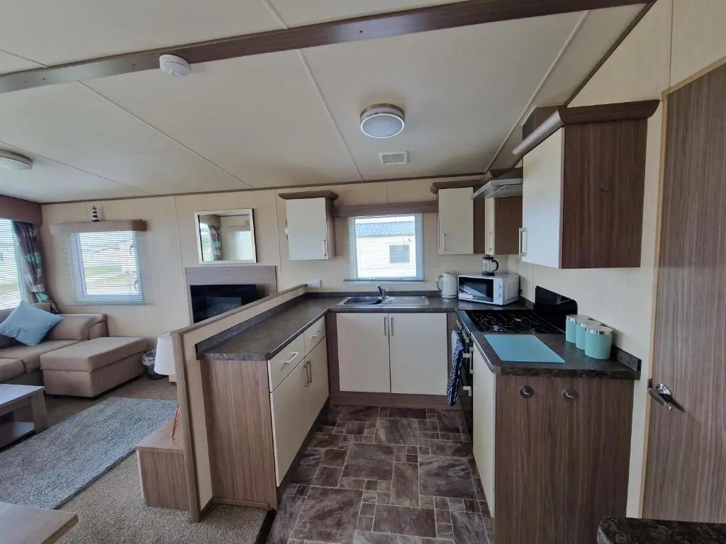 a small kitchen with a stove and a couch in a room at Cladach in Lossiemouth