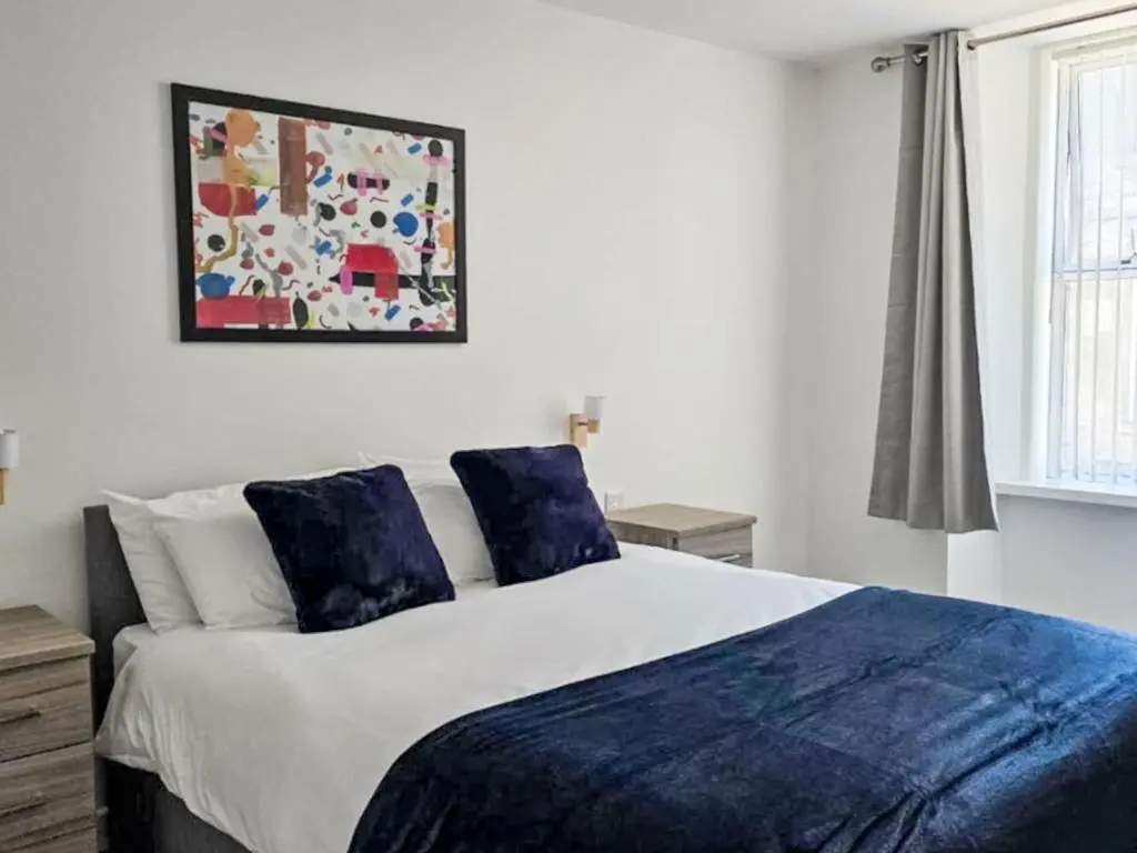 a bedroom with a large bed with blue pillows at Apartment Fishertown Apartment by Interhome in Nairn